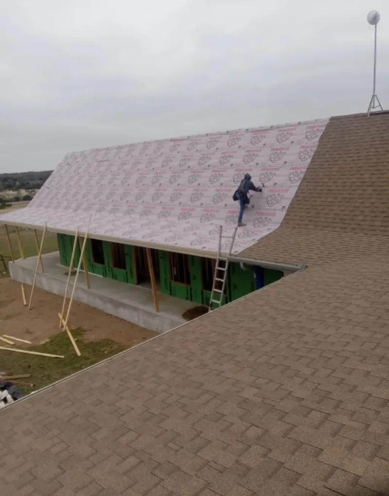 Worker preparing underlayment for a metal roof installation in Aliquippa